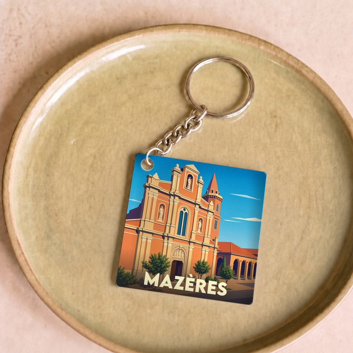 Porte-clés souvenir de la ville de Mazères avec une illustration stylisée de son église.