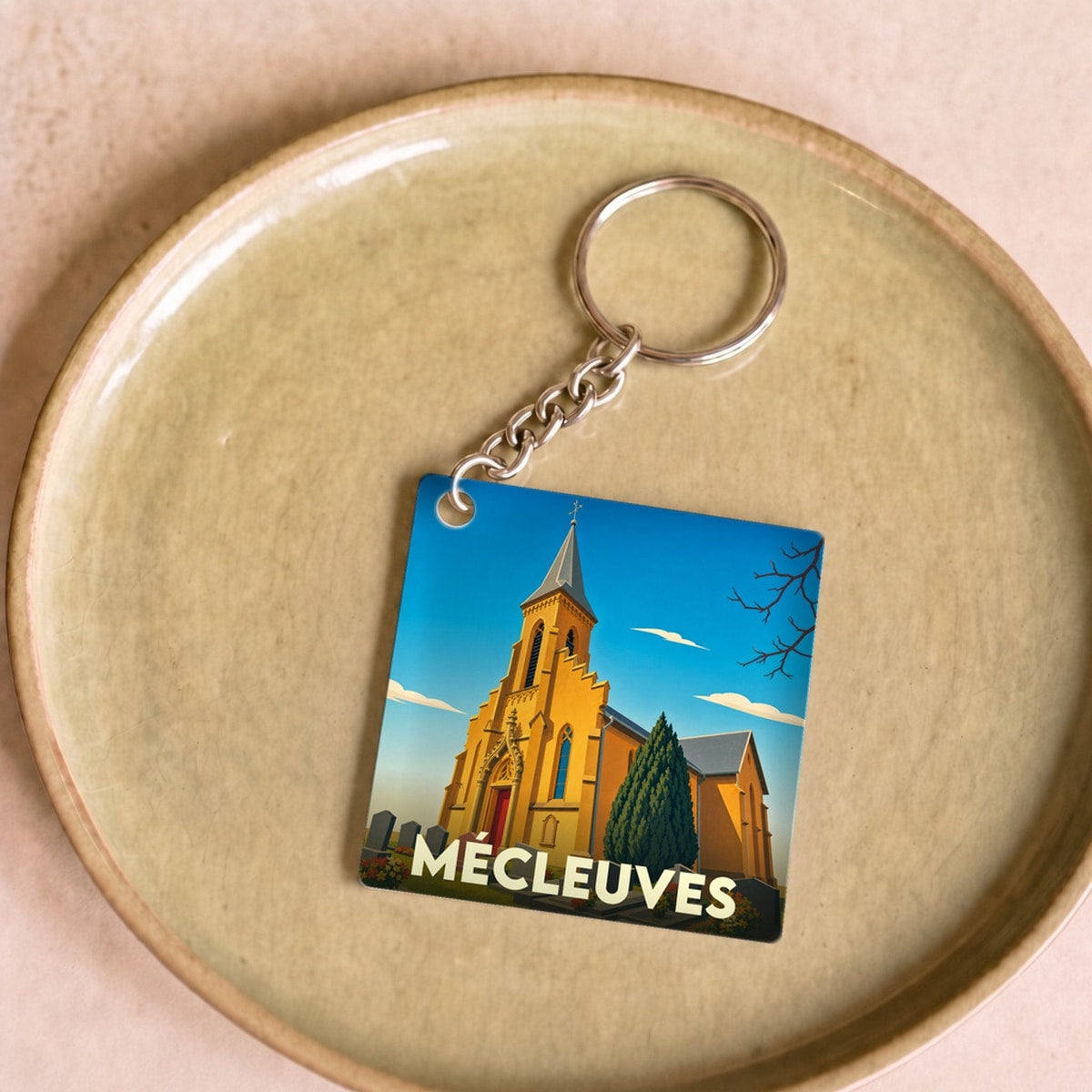 Porte-clés souvenir de la ville de Mécleuves avec une illustration stylisée de son église.