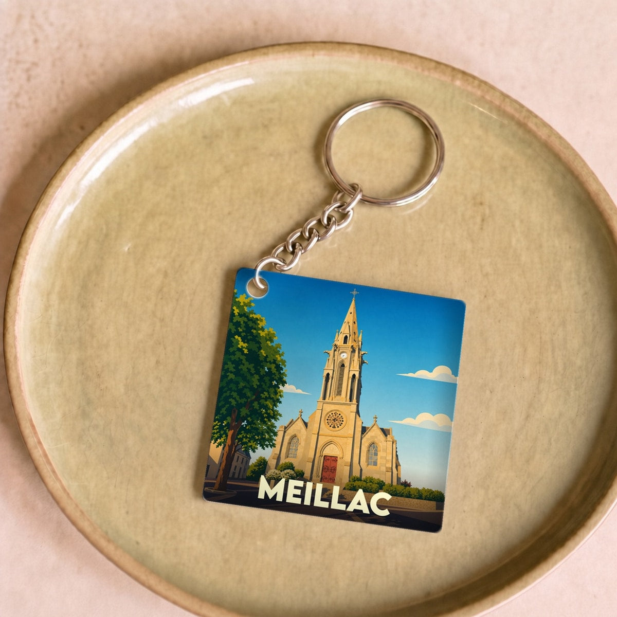 Porte-clés souvenir de la ville de Meillac avec une illustration stylisée de son église.