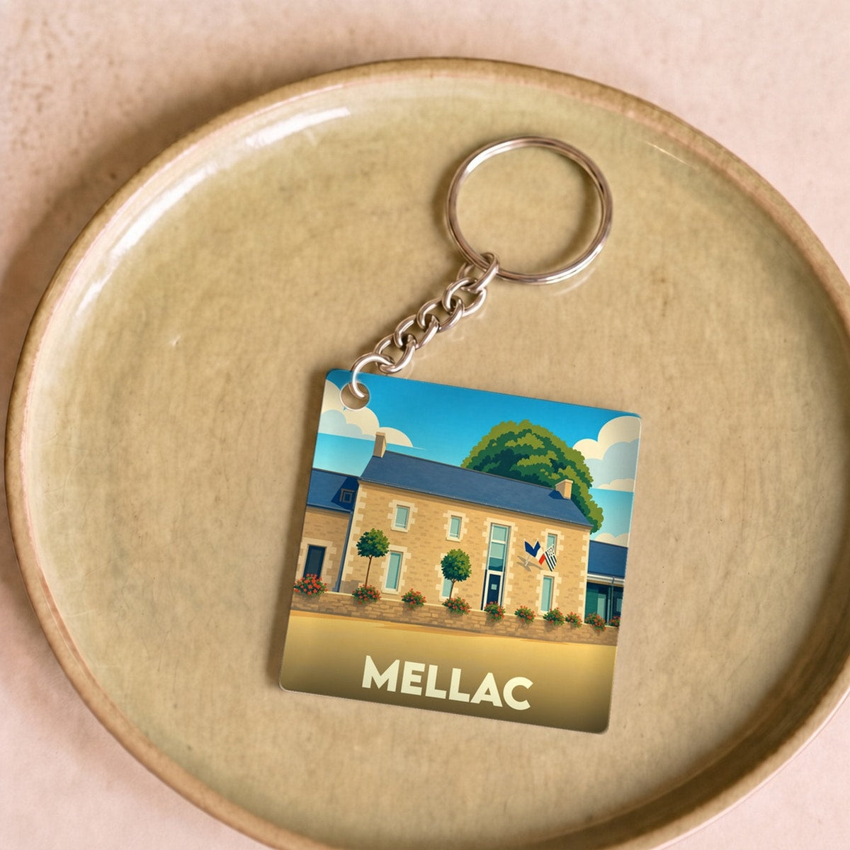 Porte-clés souvenir de la ville de Mellac avec une illustration stylisée d'un bâtiment traditionnel breton.