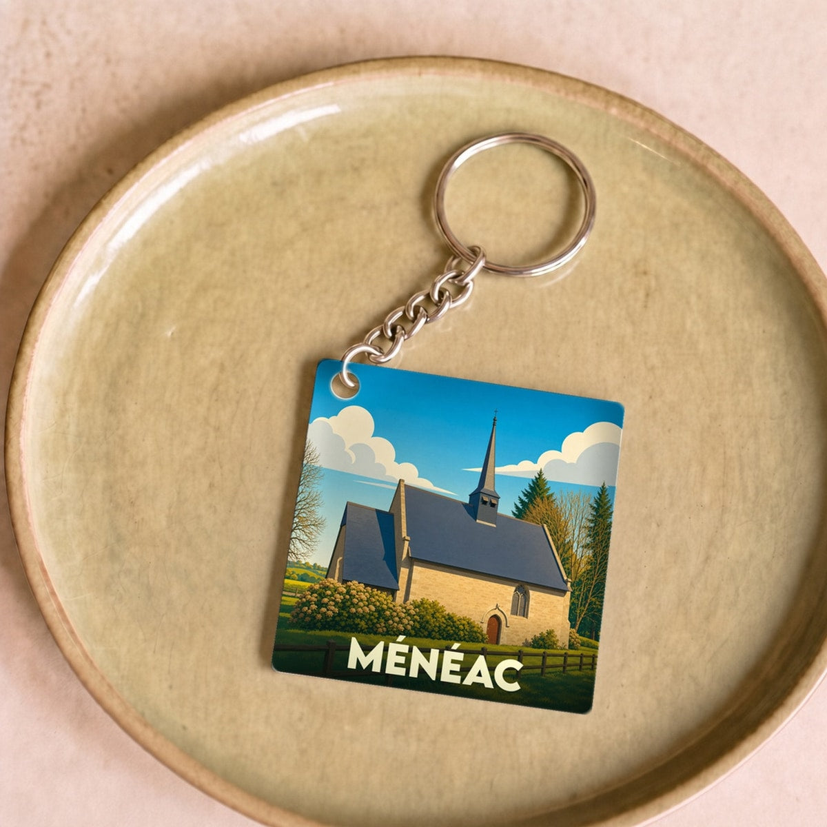 Porte-clés souvenir de la ville de Ménéac avec une illustration stylisée de sa chapelle.