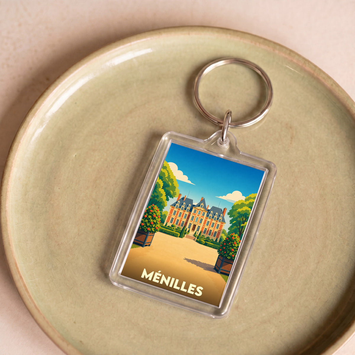 Porte-clés souvenir de la ville de Ménilles avec une illustration stylisée de son château.