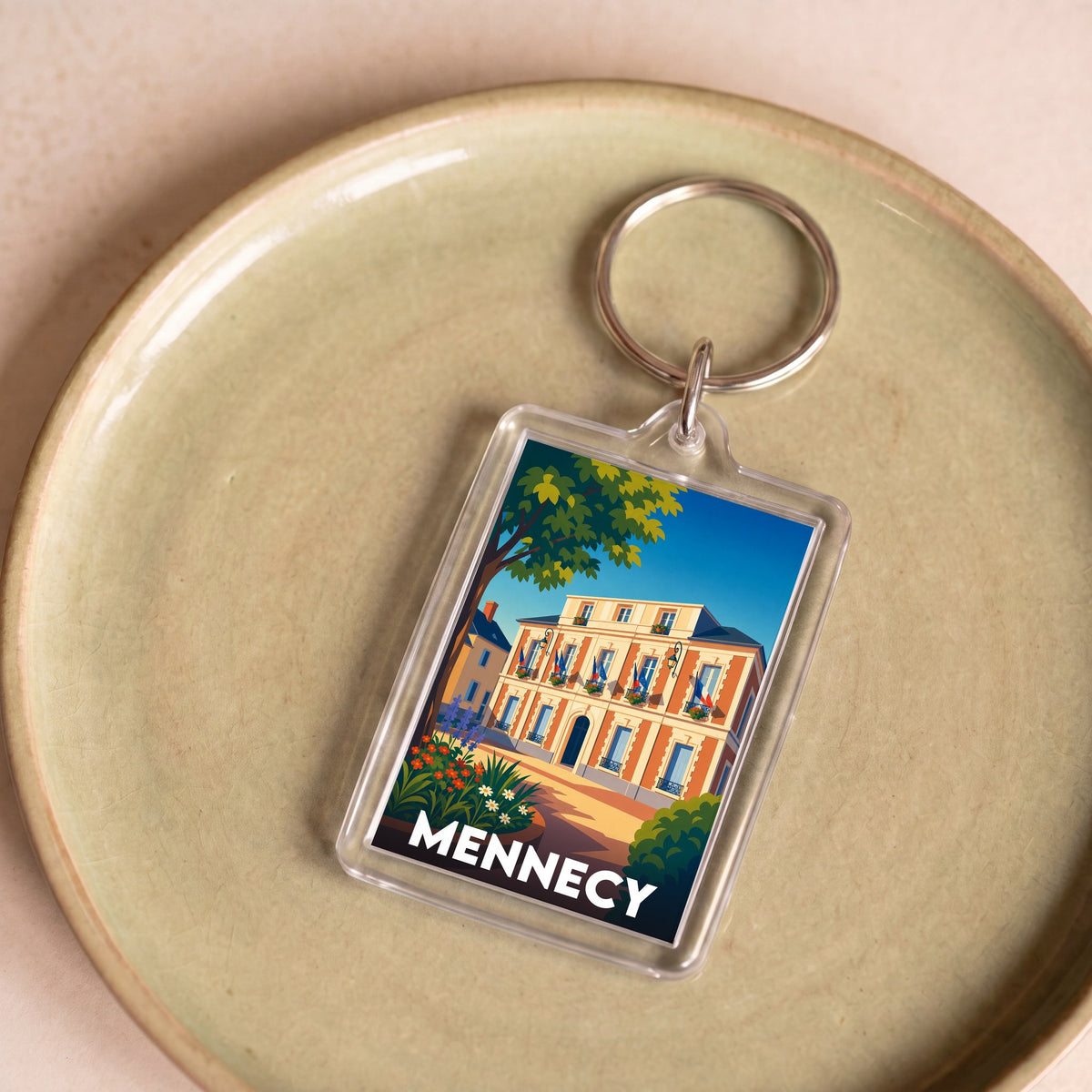 Porte-clés souvenir de la ville de Mennecy avec une illustration stylisée d'un bâtiment historique.