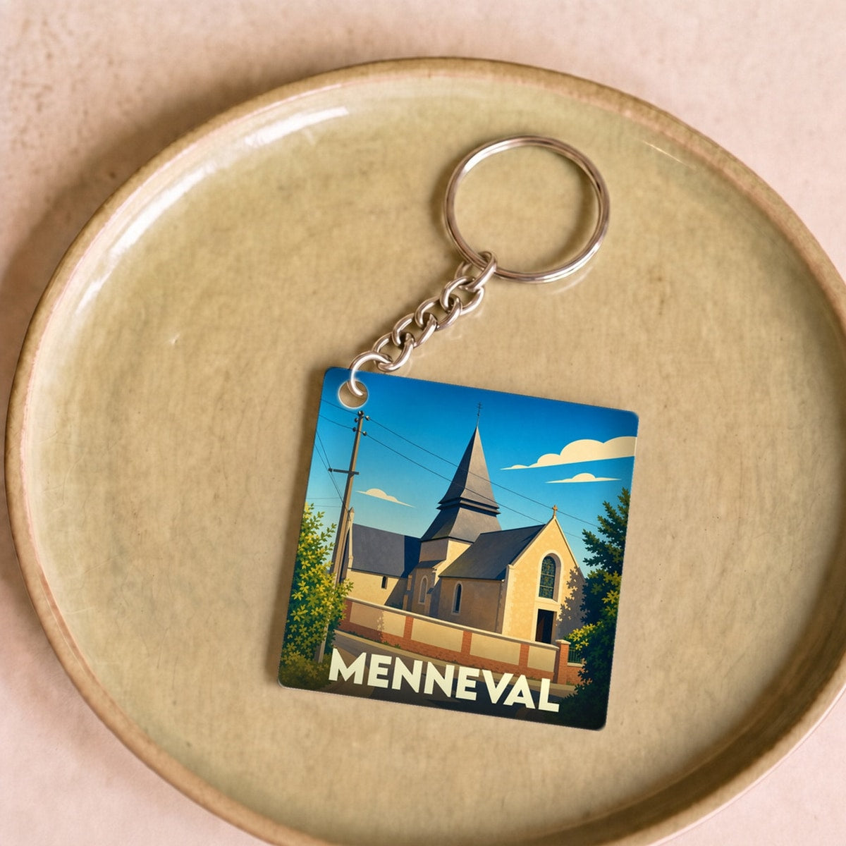 Porte-clés souvenir de la ville de Menneval avec une illustration stylisée de son église.