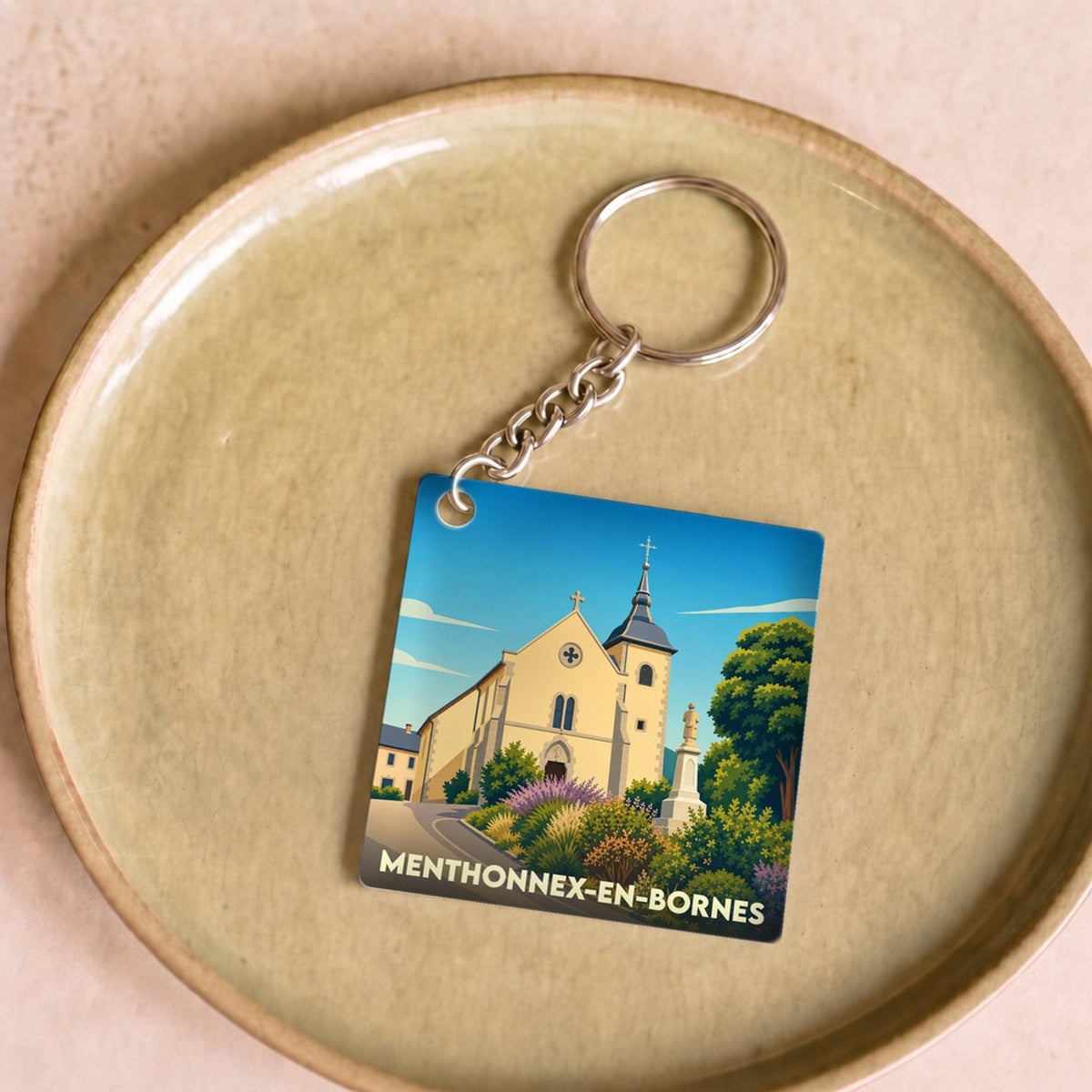 Porte-clés souvenir de la ville de Menthonnex-en-Bornes avec une illustration stylisée de son église.