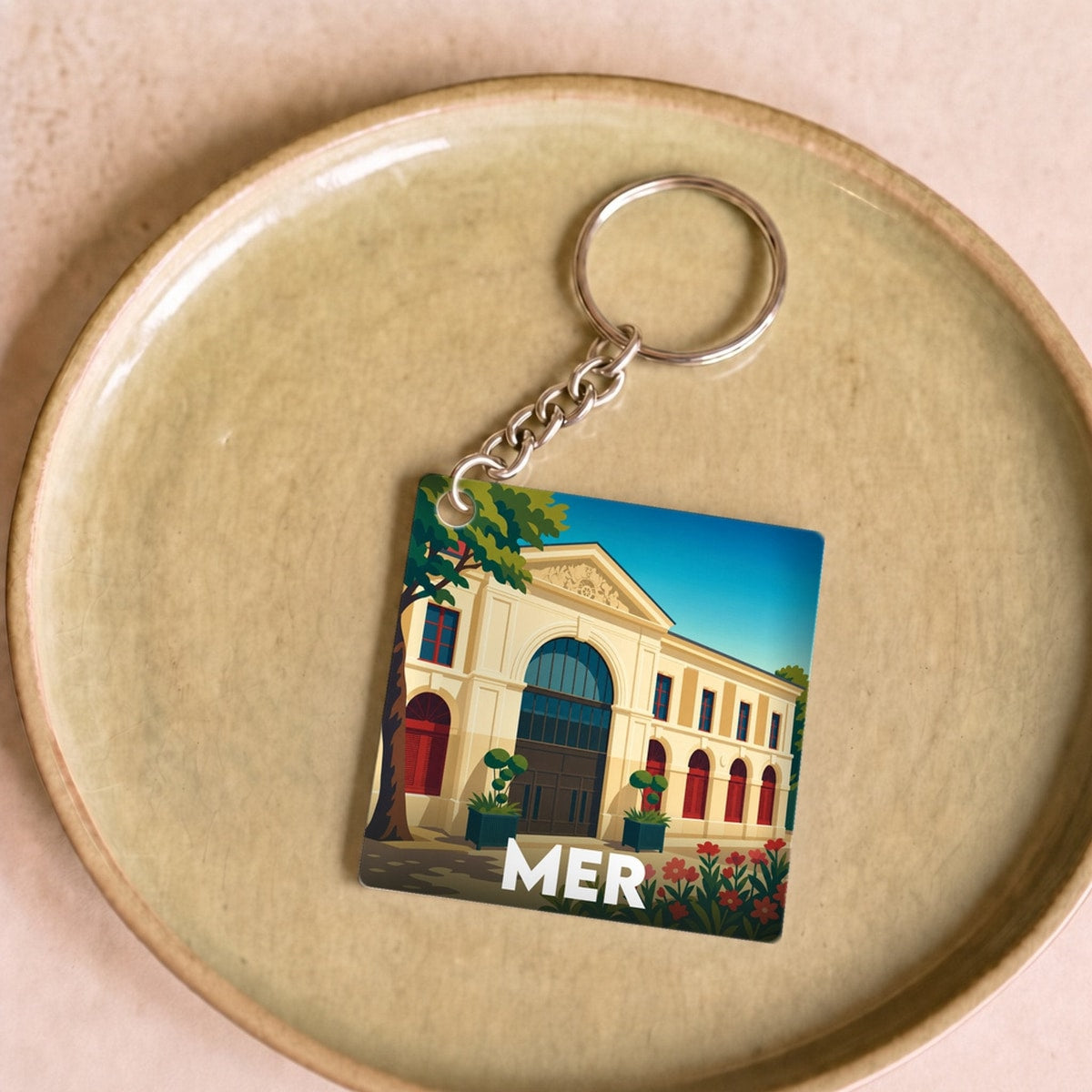 Porte-clés souvenir de la ville de Mer avec une illustration stylisée d'un bâtiment historique.