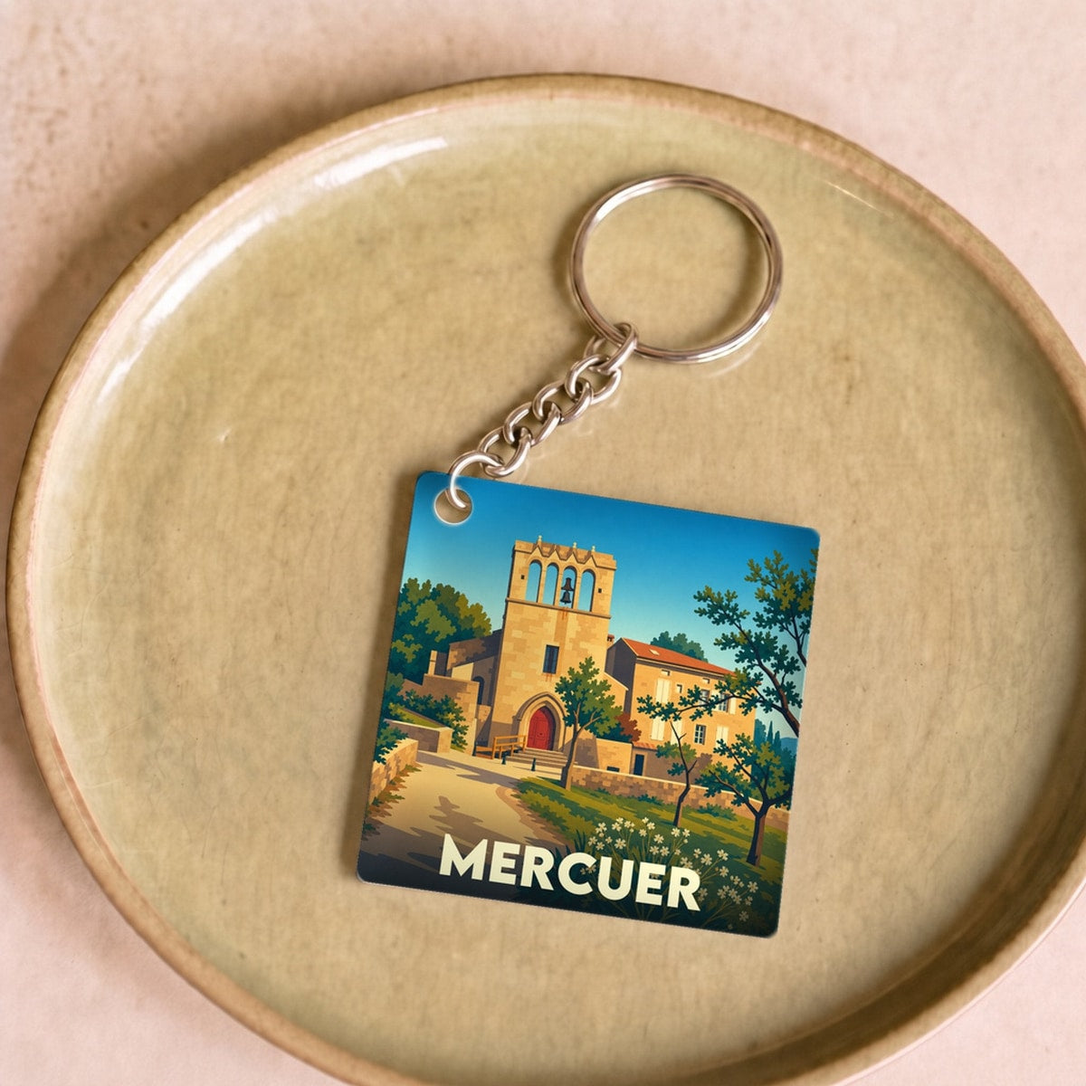 Porte-clés souvenir de la ville de Mercuer avec une illustration stylisée.