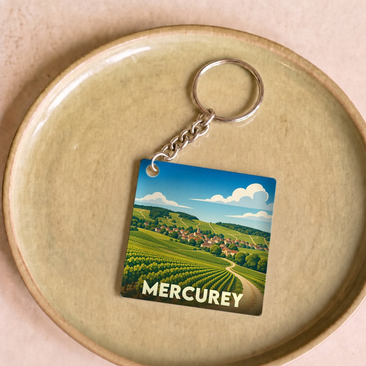 Porte-clés souvenir de la ville de Mercurey avec une illustration stylisée de vignobles.