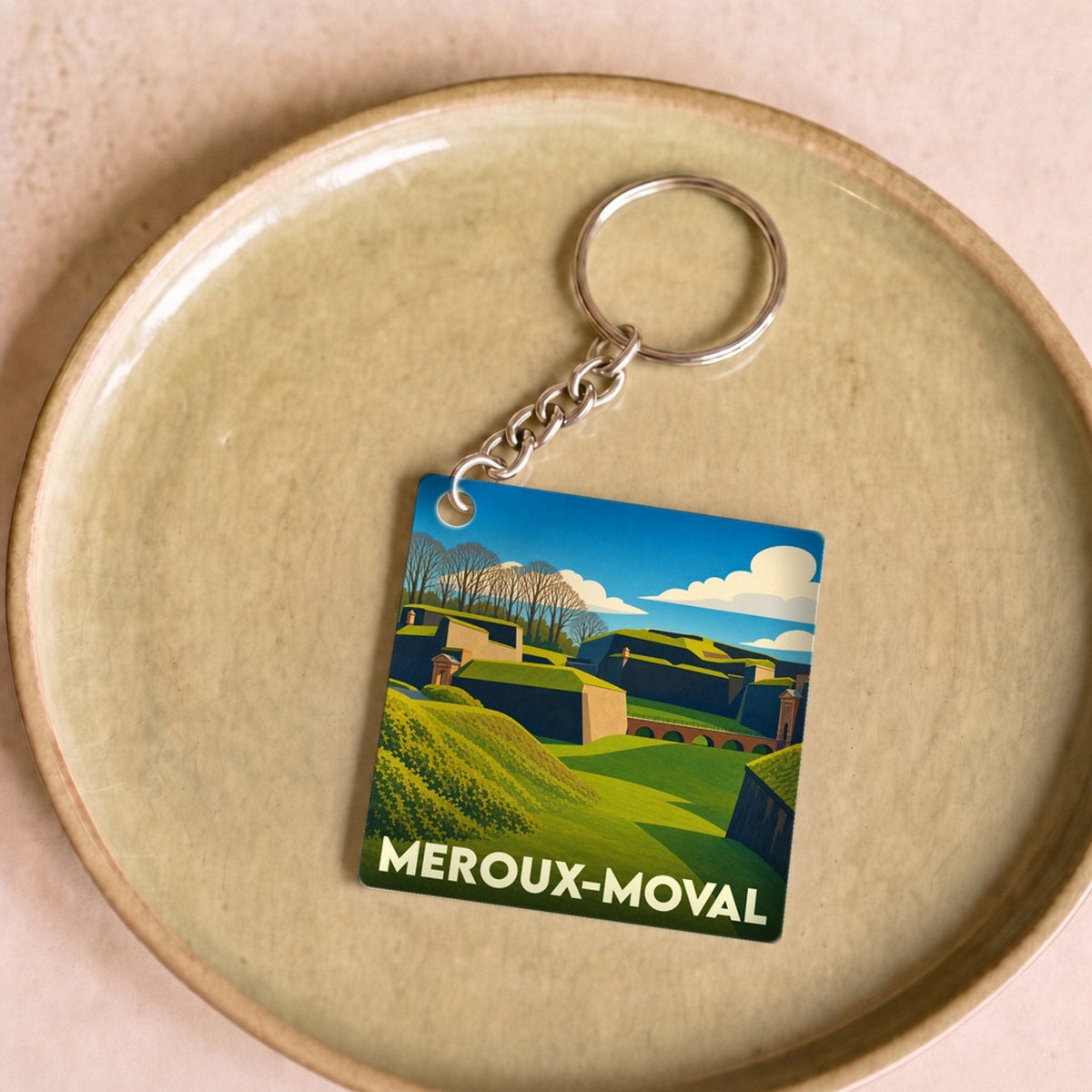 Porte-clés souvenir de la commune de Meroux-Moval avec une illustration stylisée de ses paysages et fortifications.