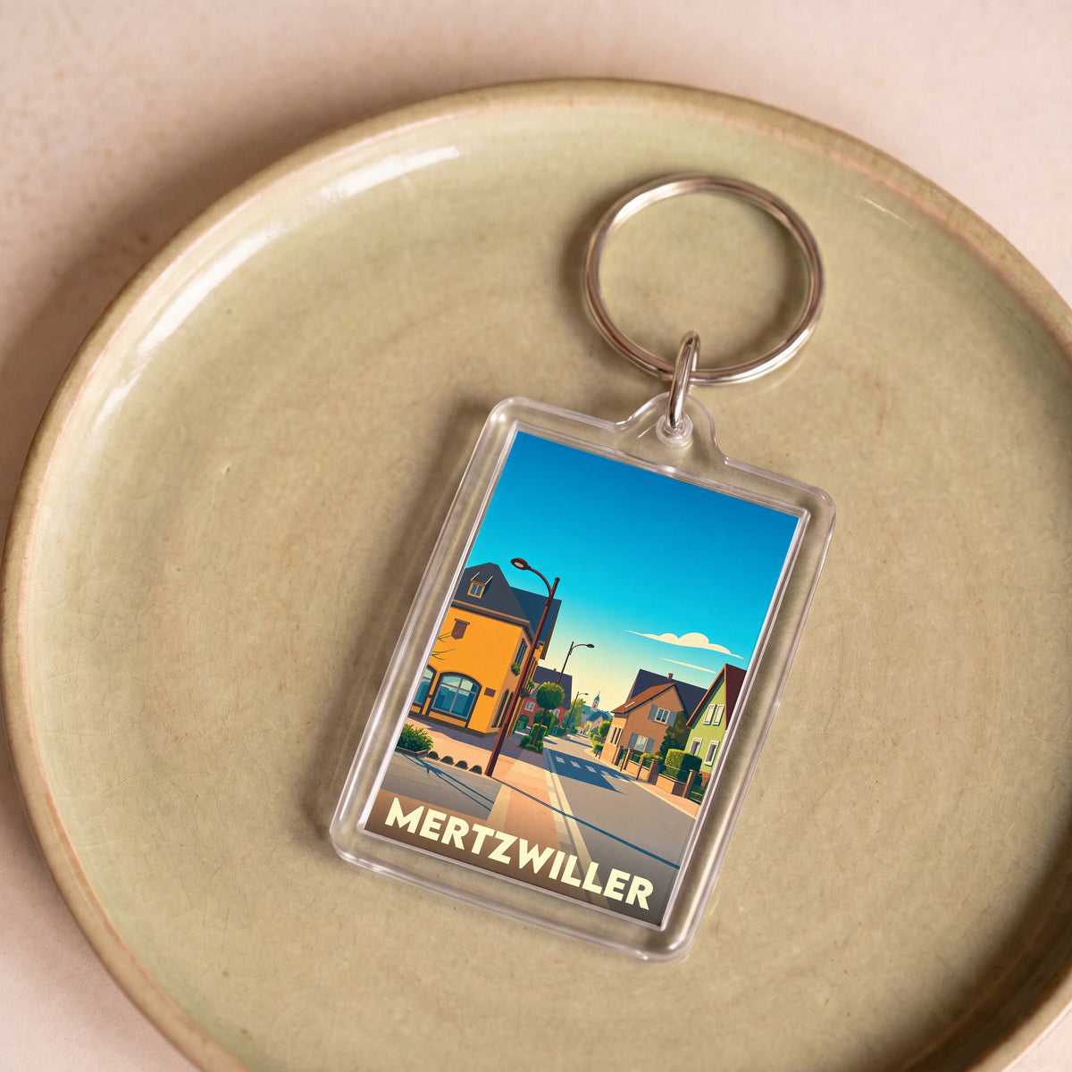 Porte-clés souvenir de la ville de Mertzwiller avec une illustration stylisée d'une rue typique.