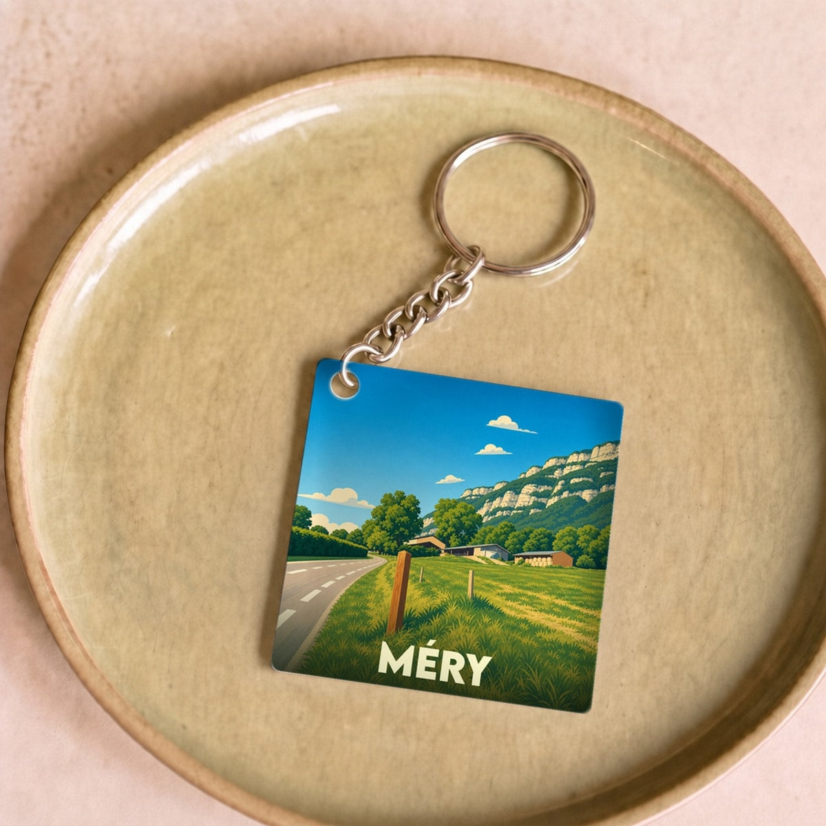 Porte-clés souvenir de la ville de Méry avec une illustration stylisée d'un paysage de campagne.