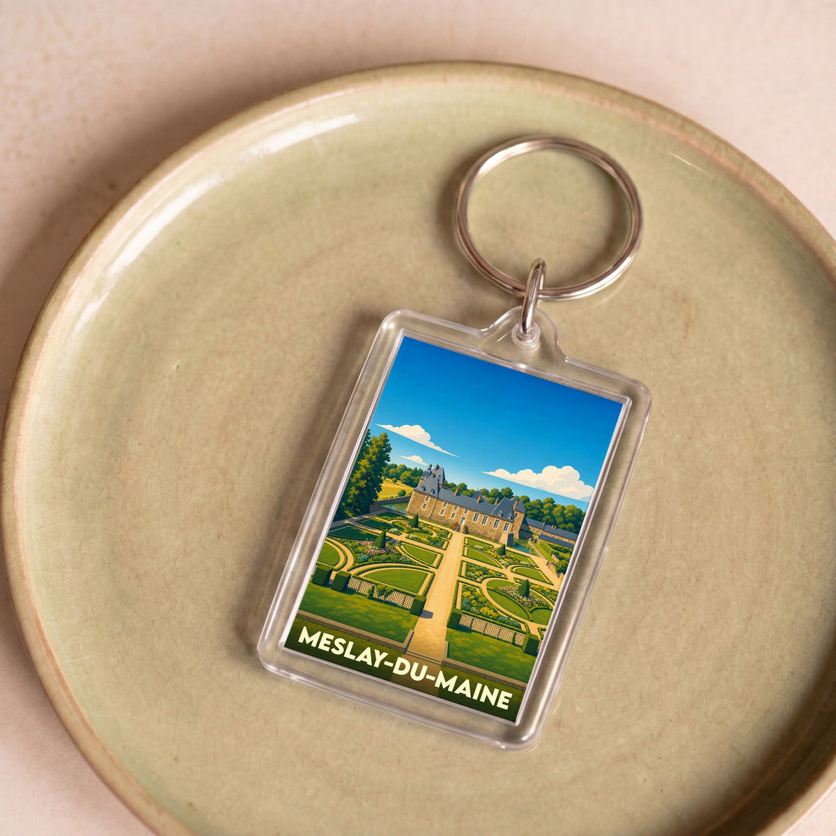 Porte-clés souvenir de la ville de Meslay-du-Maine avec une illustration stylisée de son château et de ses jardins.
