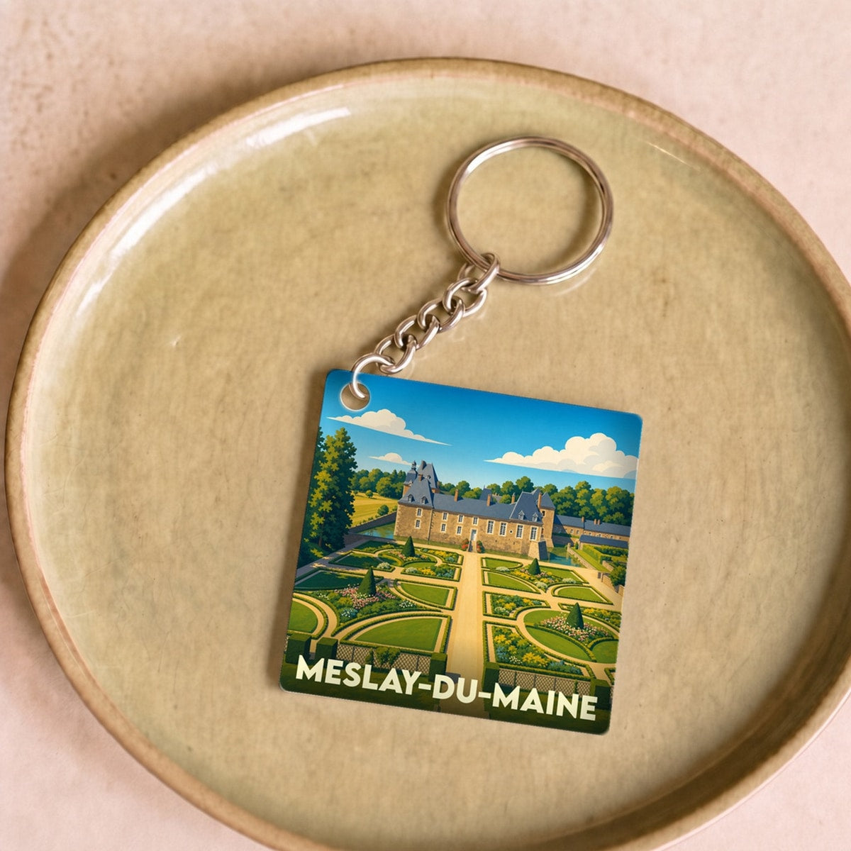 Porte-clés souvenir de la ville de Meslay-du-Maine avec une illustration stylisée de son château et de ses jardins.