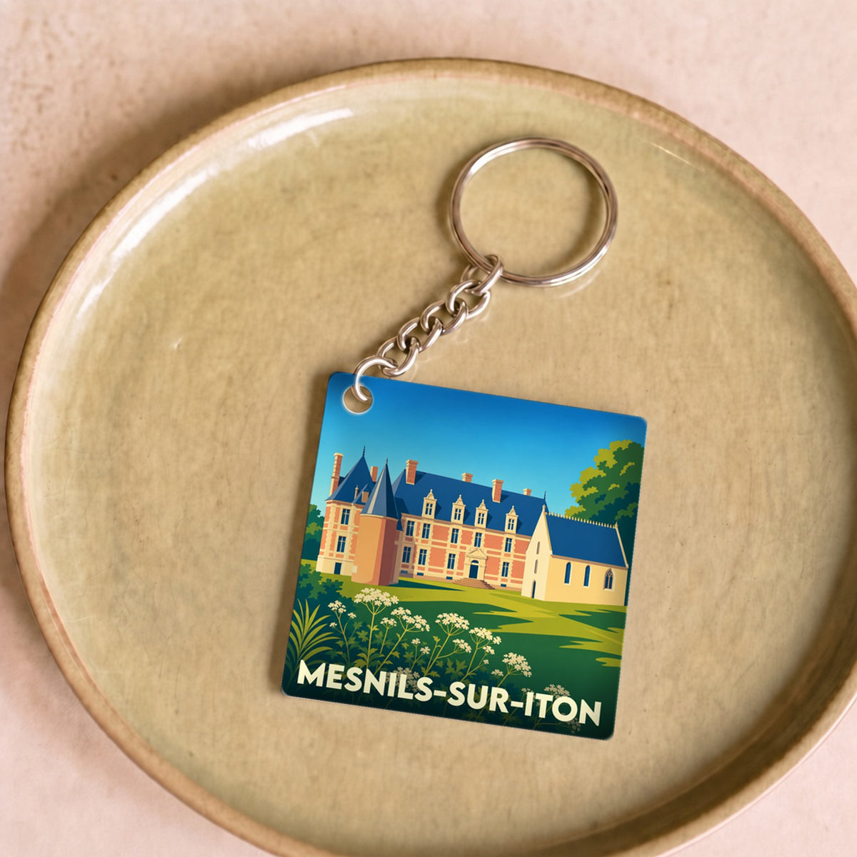 Porte-clés souvenir de la ville de Mesnils-sur-Iton avec une illustration stylisée d'un château.