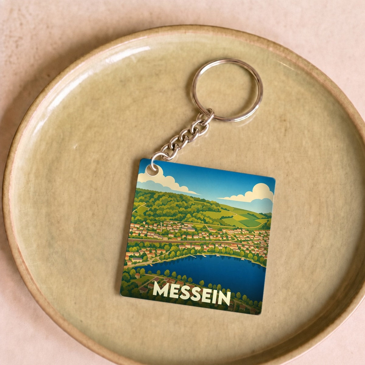 Porte-clés souvenir de la ville de Messein avec une illustration stylisée de ses paysages.