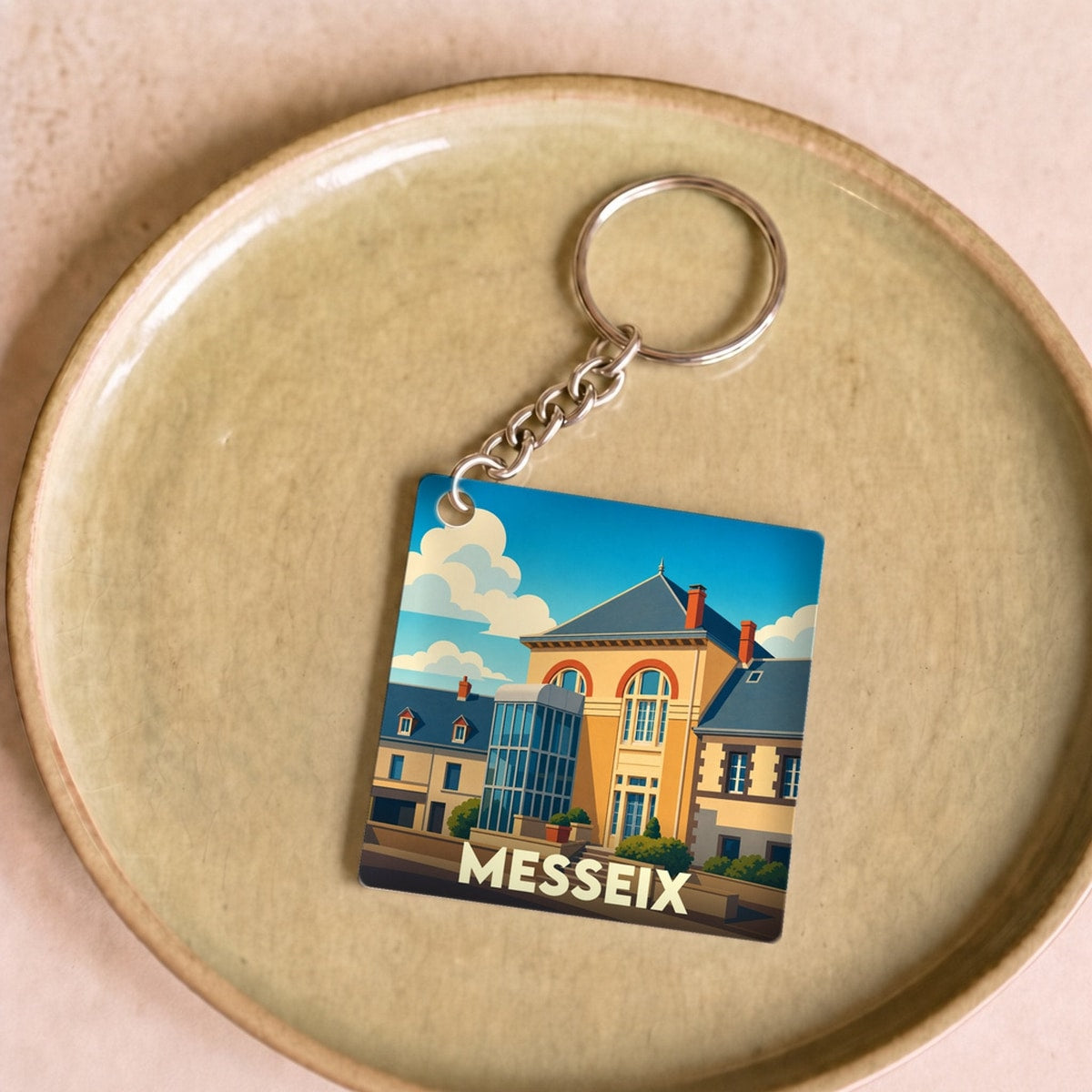 Porte-clés souvenir de la ville de Messeix avec une illustration stylisée de son architecture.