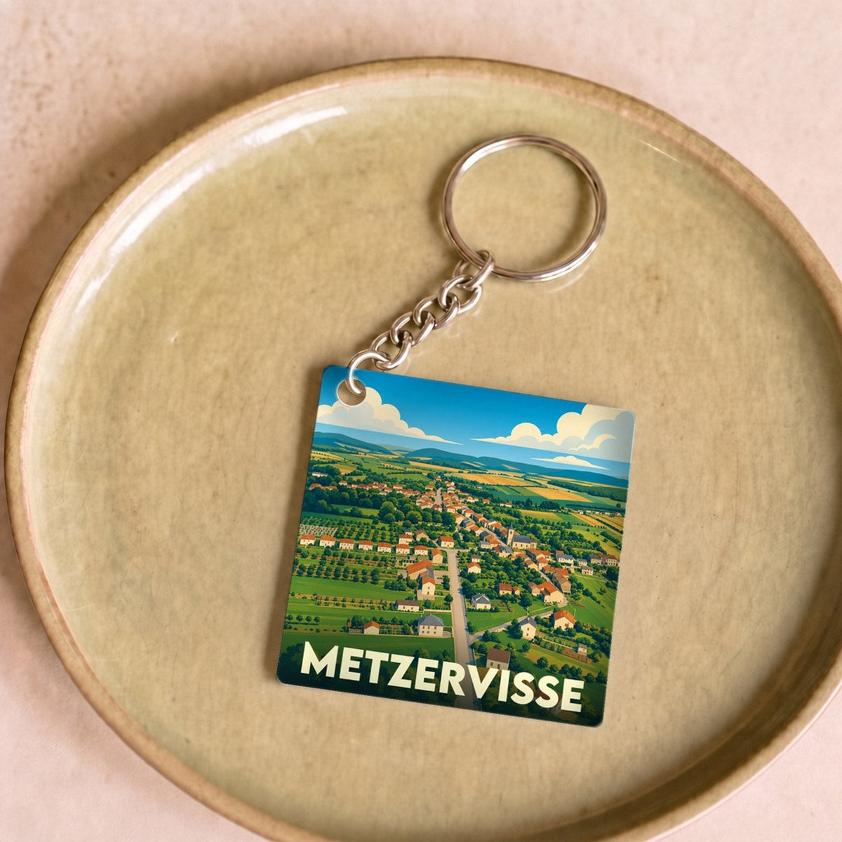 Porte-clés souvenir de la ville de Metzervisse avec une illustration stylisée de son paysage rural.