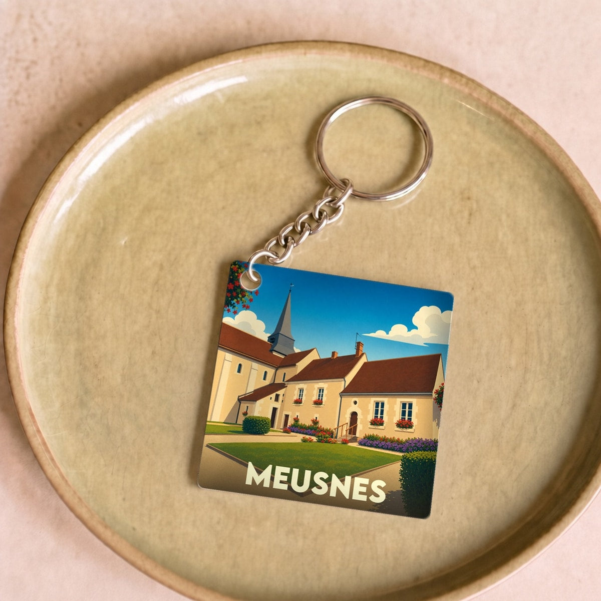 Porte-clés souvenir de la ville de Meusnes avec une illustration stylisée de son église et de ses maisons.