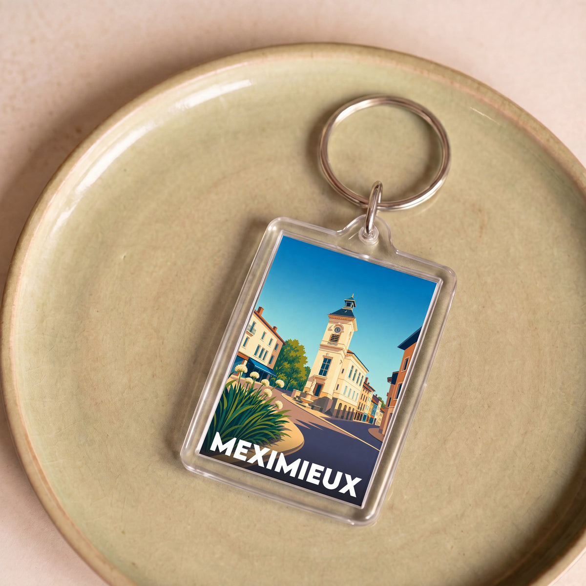 Porte-clés souvenir de la ville de Meximieux avec une illustration stylisée de son architecture.