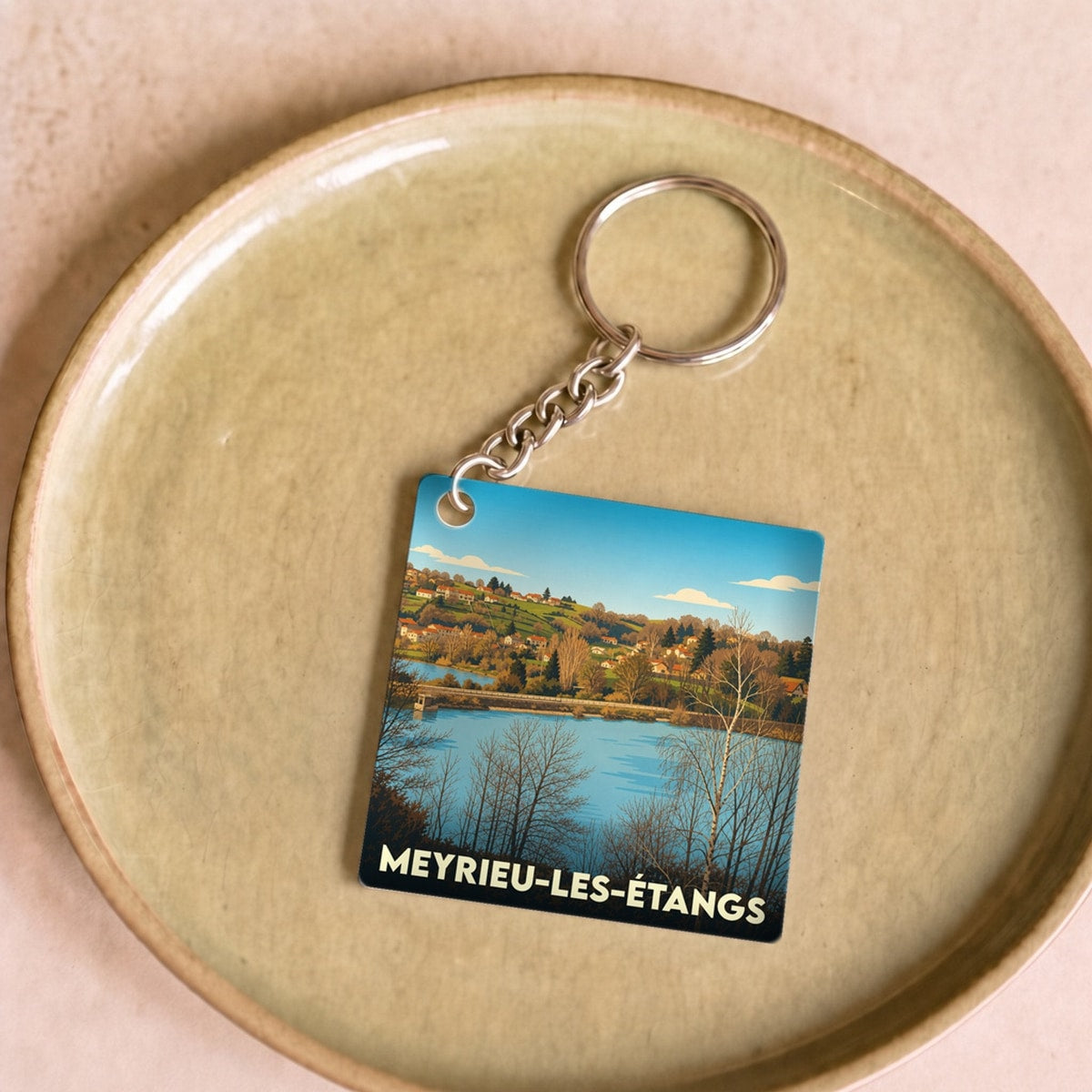 Porte-clés souvenir de la ville de Meyrieu-les-Étangs avec une illustration stylisée.