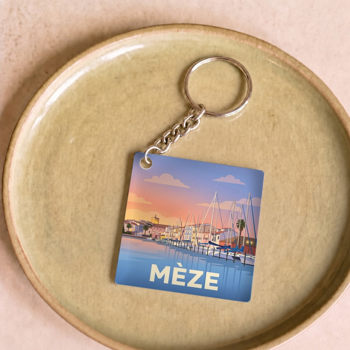 Porte-clés souvenir de la ville de Mèze avec une illustration stylisée.