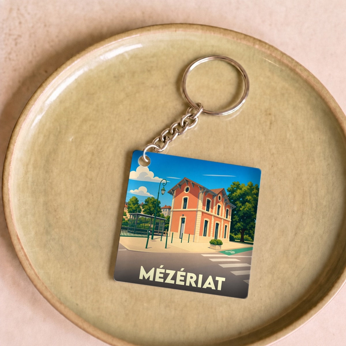 Porte-clés souvenir de la ville de Mézériat avec une illustration stylisée de sa gare.