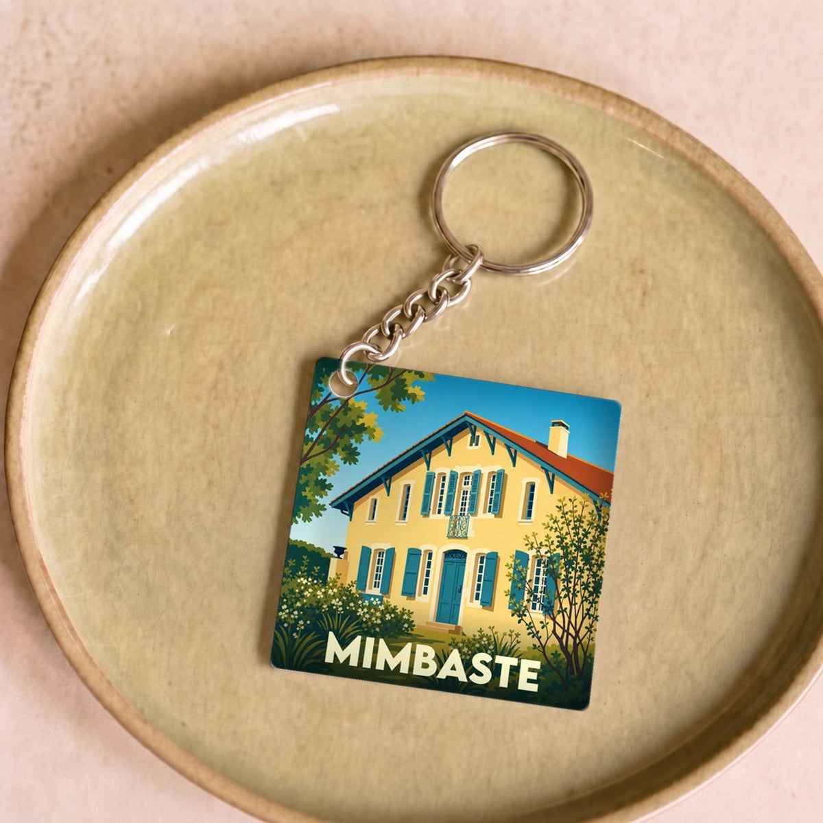 Porte-clés souvenir de la ville de Mimbaste avec une illustration stylisée d'une maison landaise.