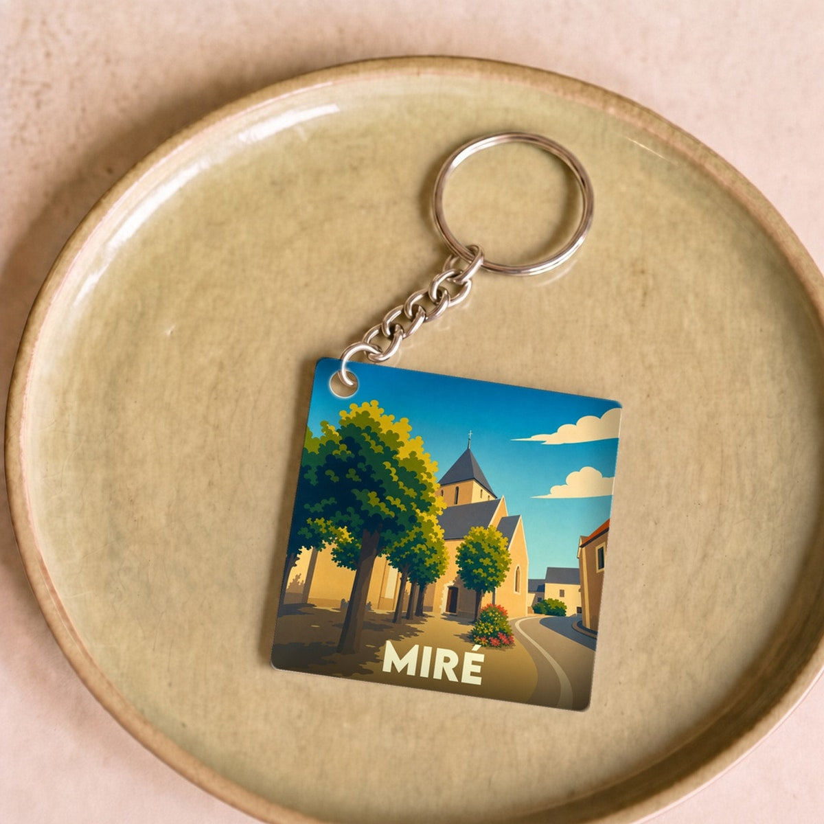Porte-clés souvenir de la ville de Miré avec une illustration stylisée et colorée.