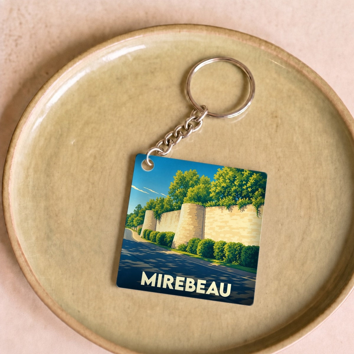 Porte-clés souvenir de la ville de Mirebeau avec une illustration stylisée de ses remparts.