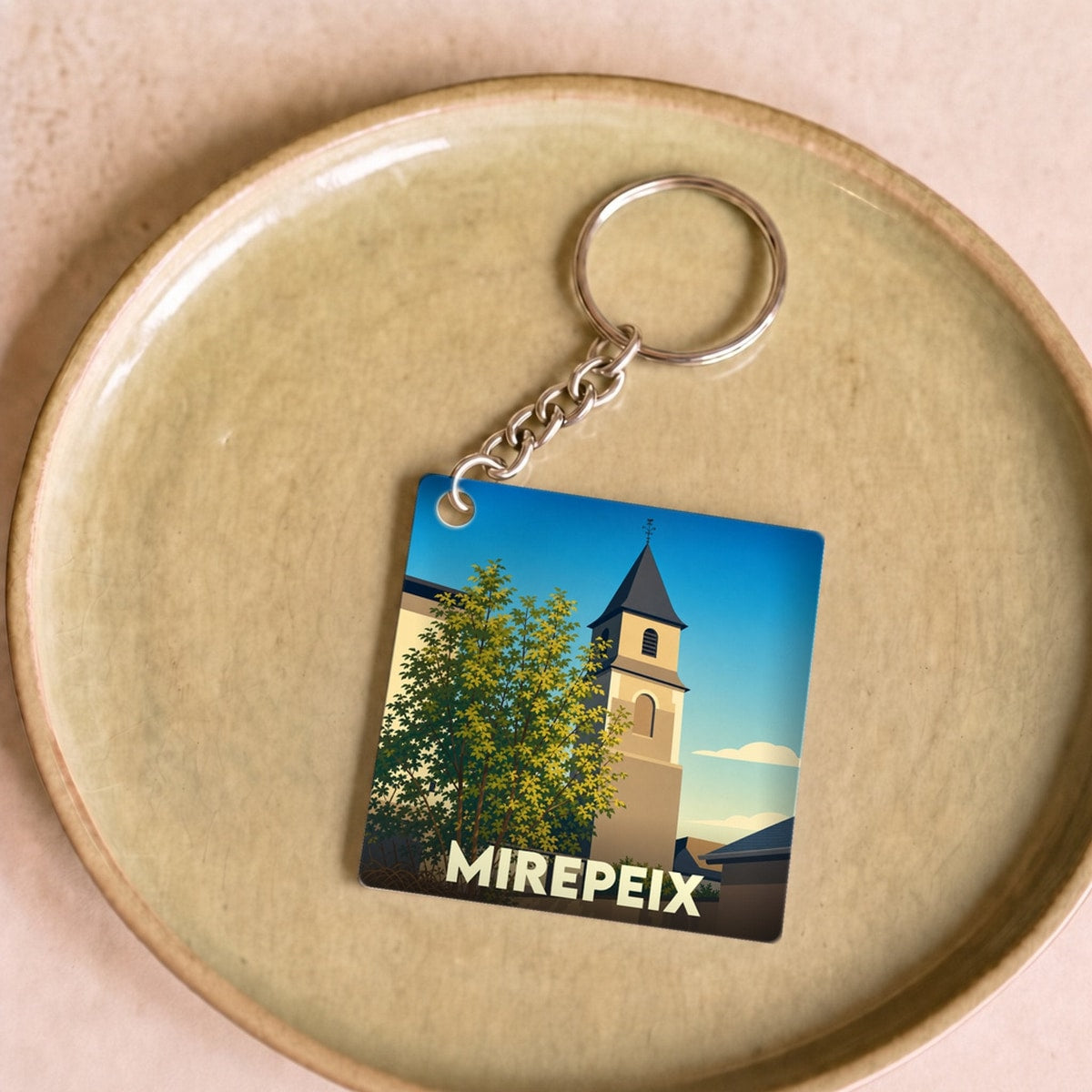 Porte-clés souvenir de la ville de Mirepeix avec une illustration stylisée de son église.