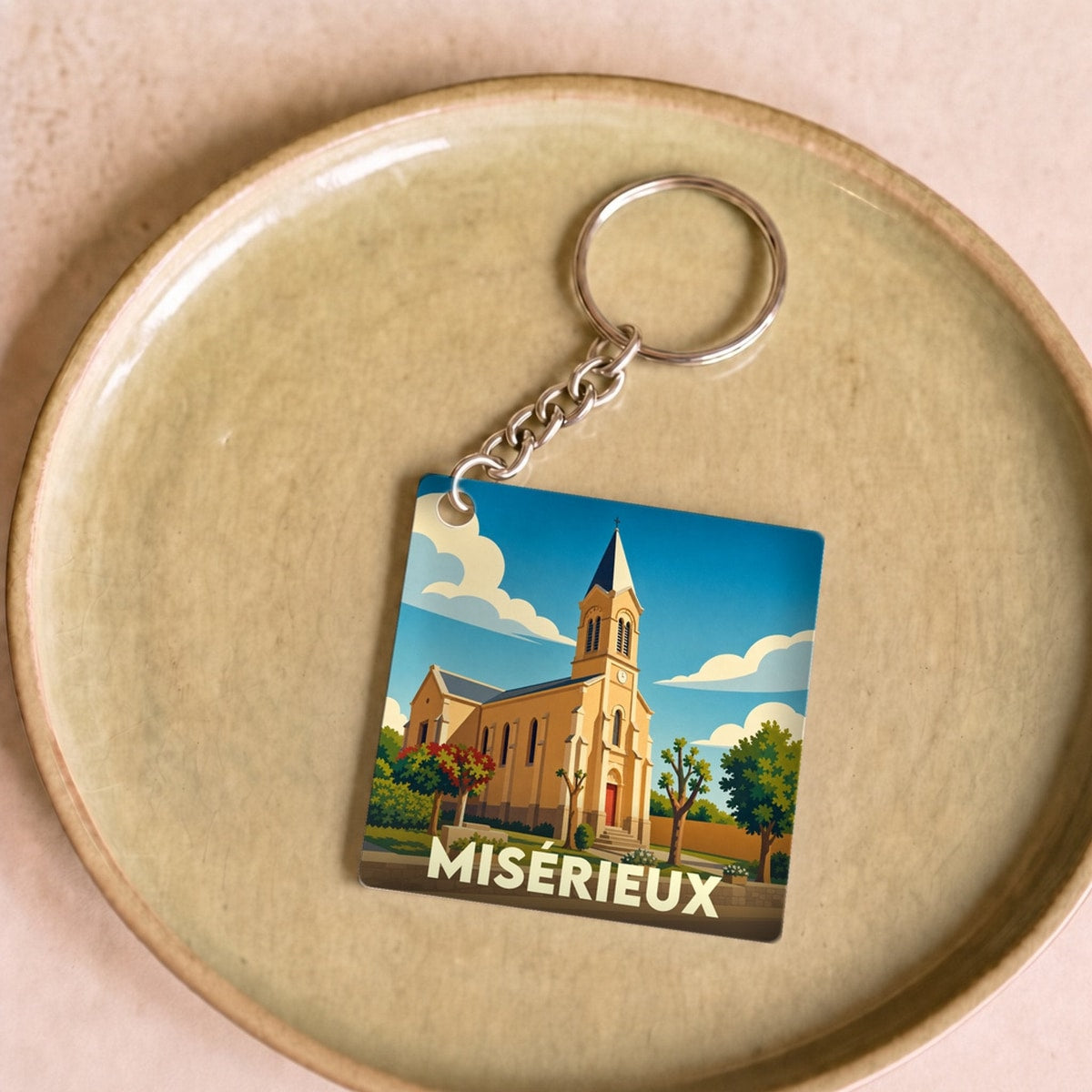 Porte-clés souvenir de la ville de Misérieux avec une illustration stylisée de son église.