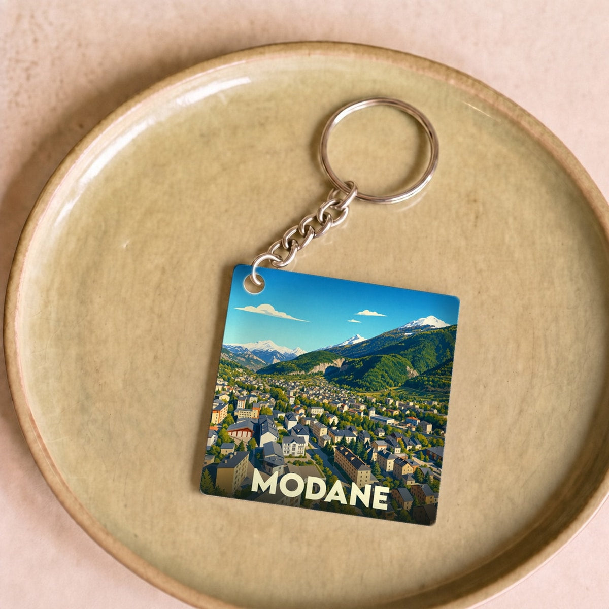 Porte-clés souvenir de la ville de Modane avec une illustration stylisée d'un paysage montagneux.