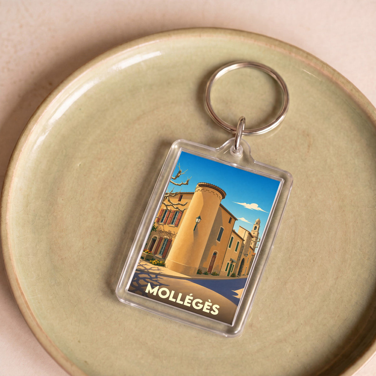 Porte-clés souvenir de la ville de Mollégès avec une illustration stylisée de son architecture provençale.