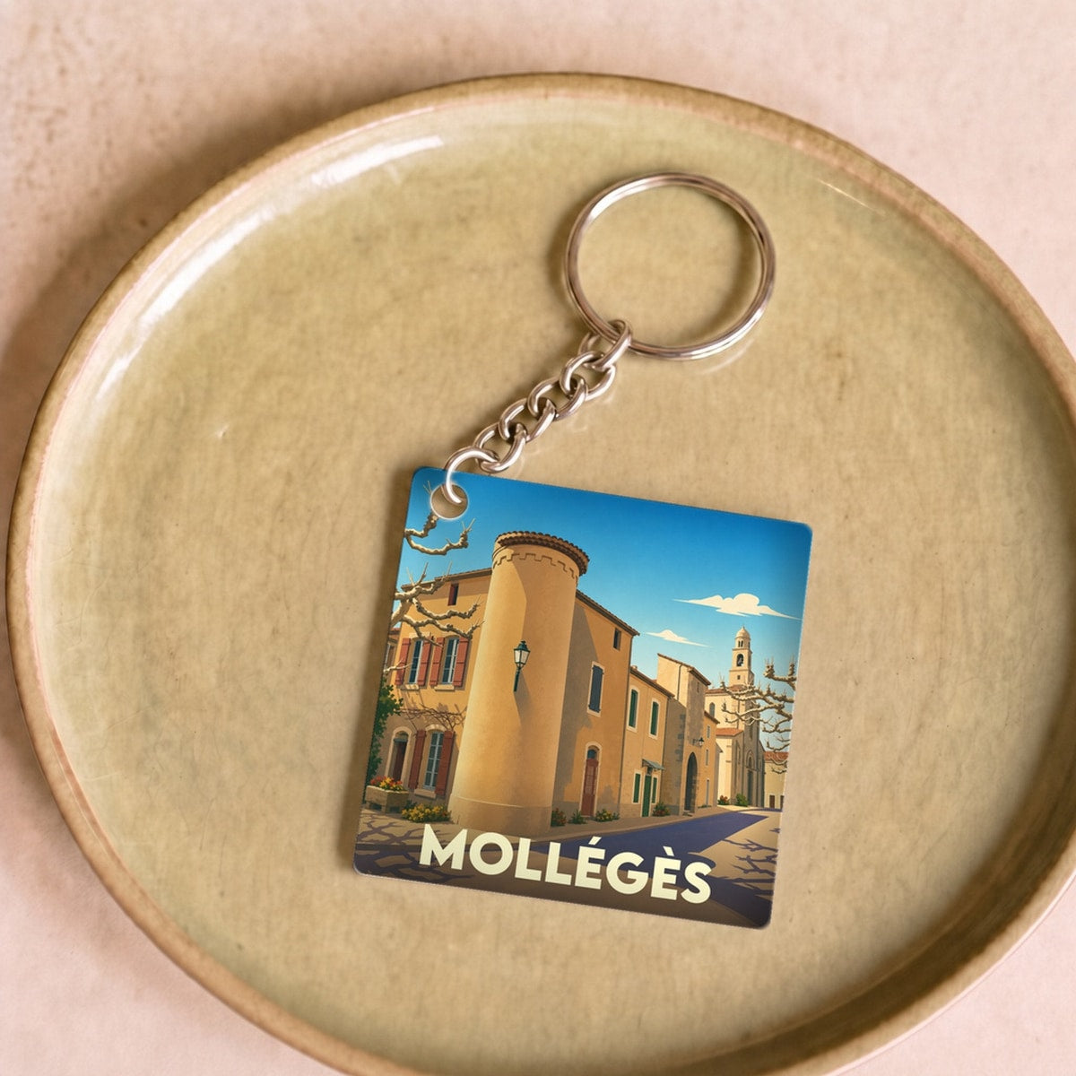 Porte-clés souvenir de la ville de Mollégès avec une illustration stylisée de son architecture provençale.