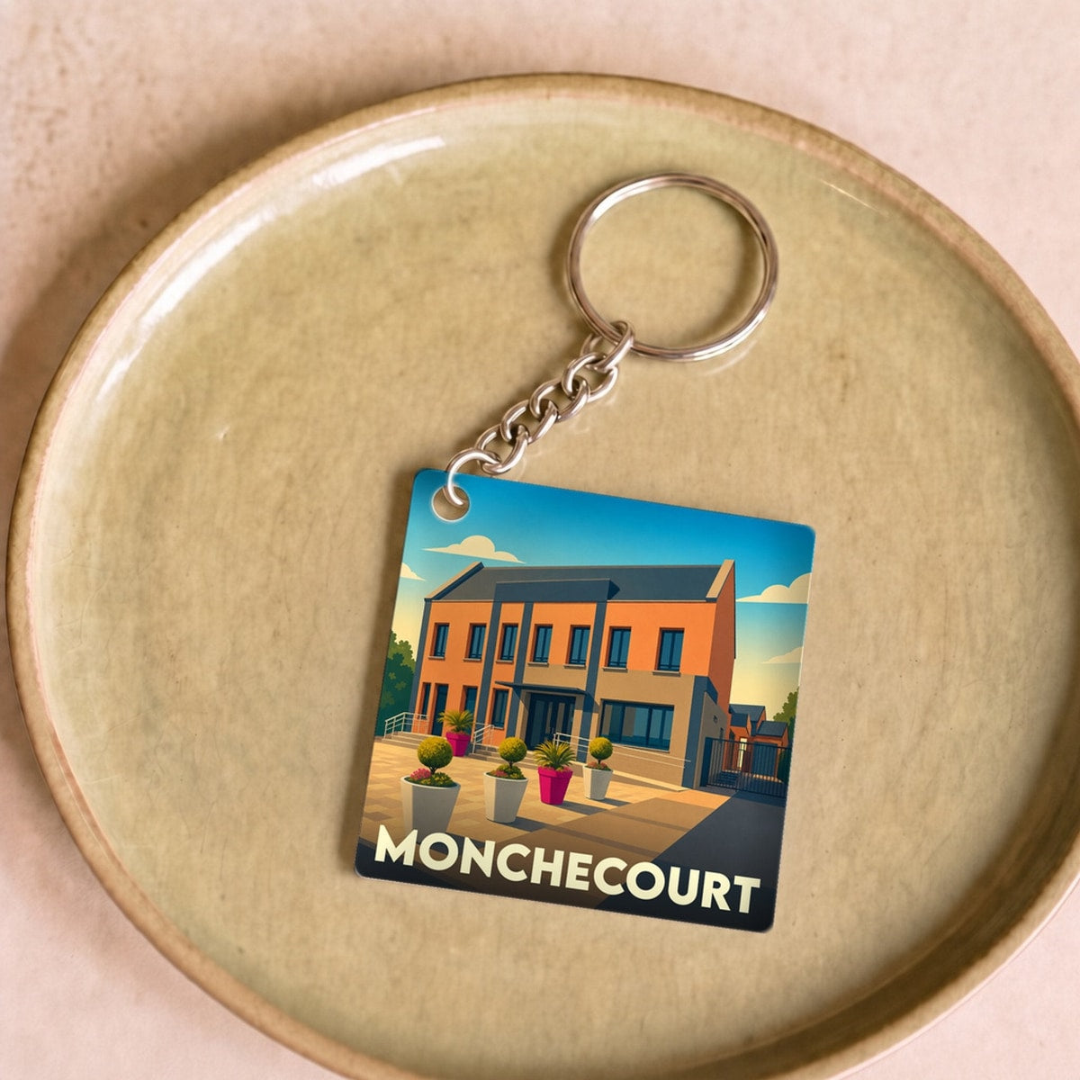 Porte-clés souvenir de la ville de Monchecourt avec une illustration stylisée.