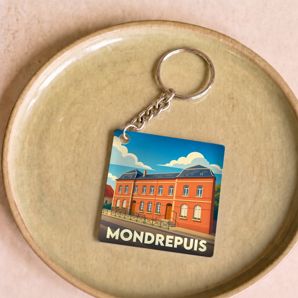 Porte-clés souvenir de la ville de Mondrepuis avec une illustration stylisée.