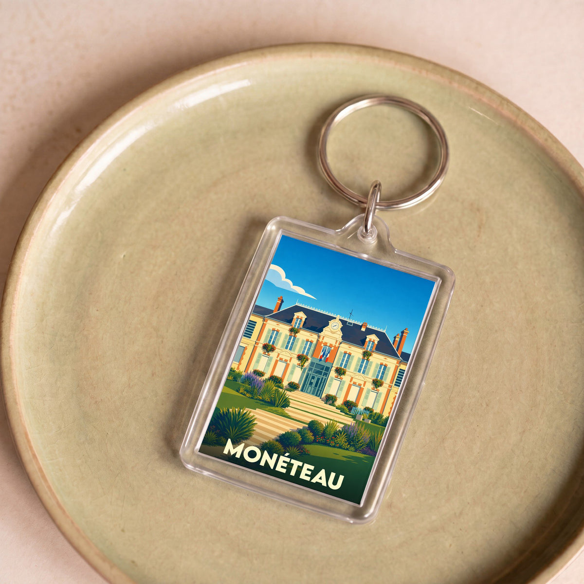 Porte-clés souvenir de la ville de Monéteau avec une illustration stylisée de la mairie.