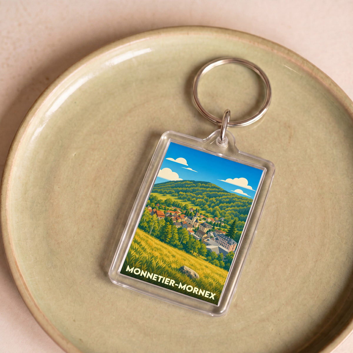 Porte-clés souvenir de la ville de Monnetier-Mornex avec une illustration stylisée de son paysage.