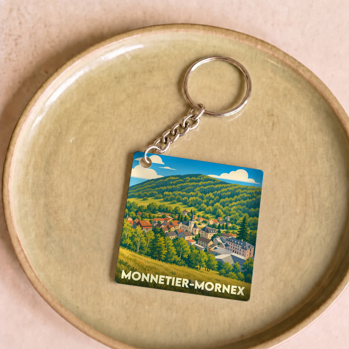 Porte-clés souvenir de la ville de Monnetier-Mornex avec une illustration stylisée de son paysage.