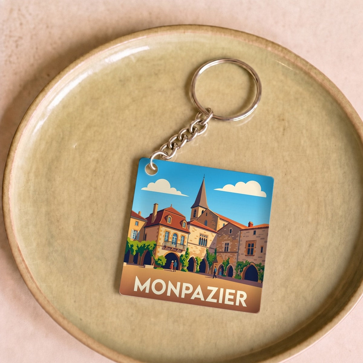 Porte-clés souvenir de la ville de Monpazier avec une illustration stylisée.