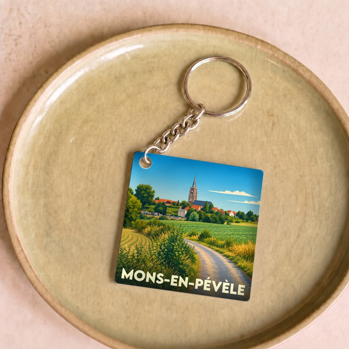 Porte-clés souvenir de la ville de Mons-en-Pévèle avec une illustration stylisée.