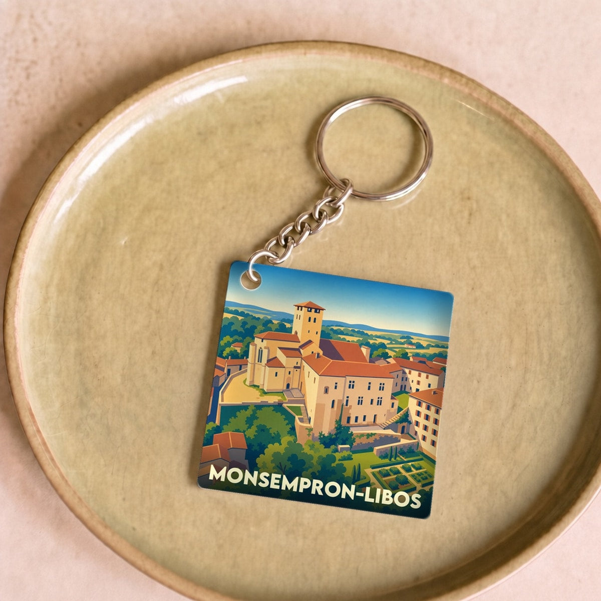 Porte-clés souvenir de la ville de Monsempron-Libos avec une illustration stylisée de son patrimoine.