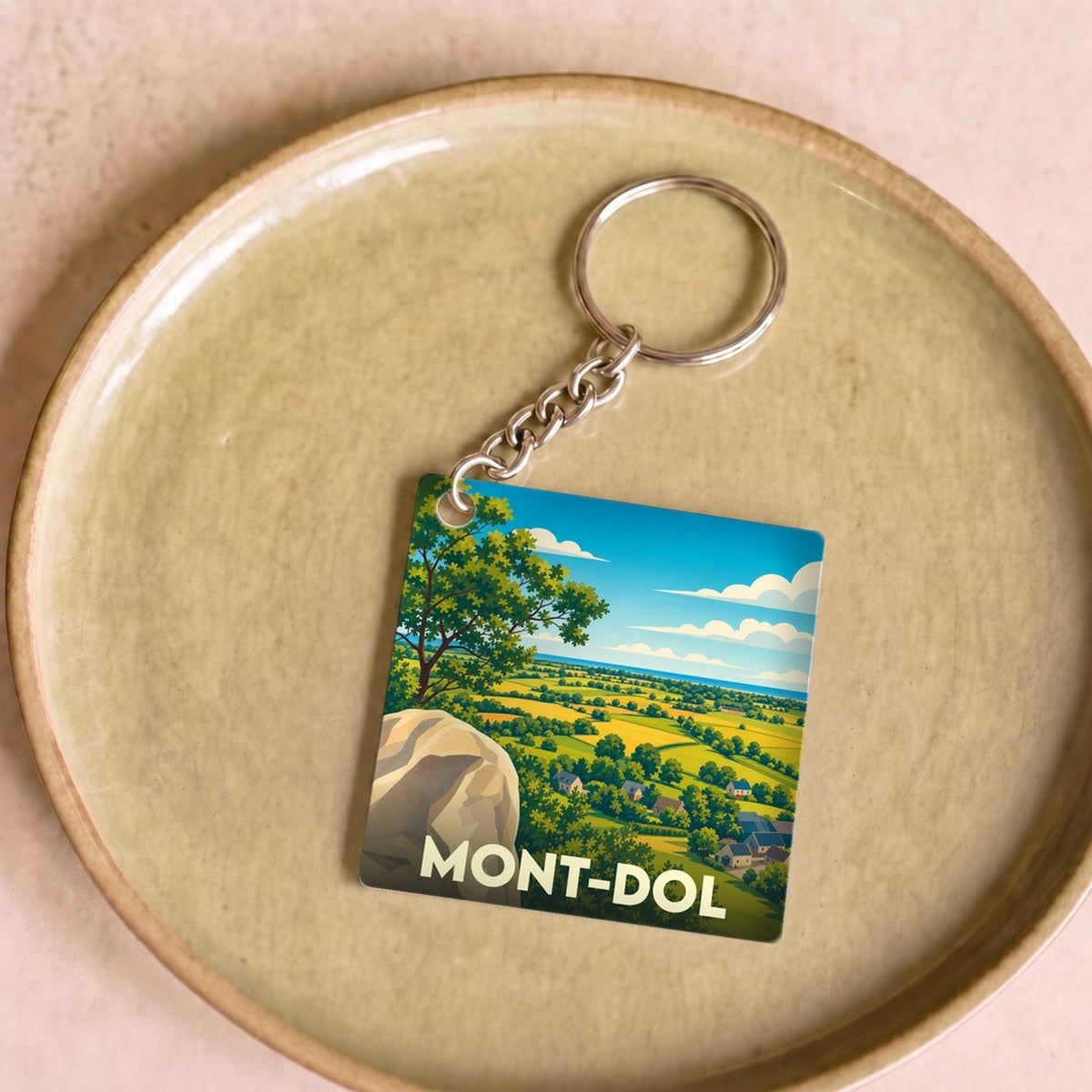 Porte-clés souvenir de la ville de Mont-Dol avec une illustration stylisée d'un paysage panoramique.