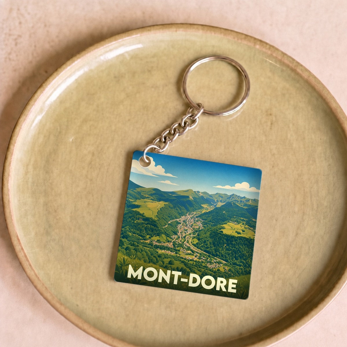Porte-clés souvenir de la ville du Mont-Dore avec une illustration stylisée d'un paysage montagneux.