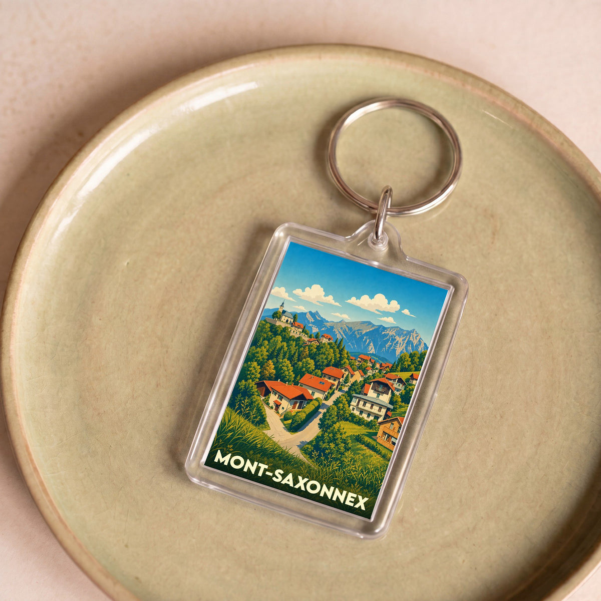 Porte-clés souvenir de la ville de Mont-Saxonnex avec une illustration stylisée de montagne.