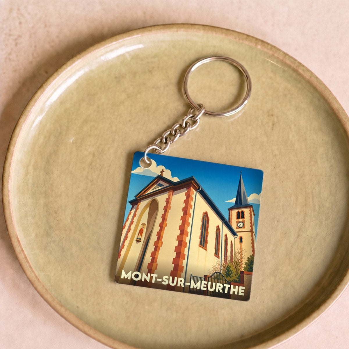 Porte-clés souvenir de la ville de Mont-sur-Meurthe avec une illustration stylisée de son église.