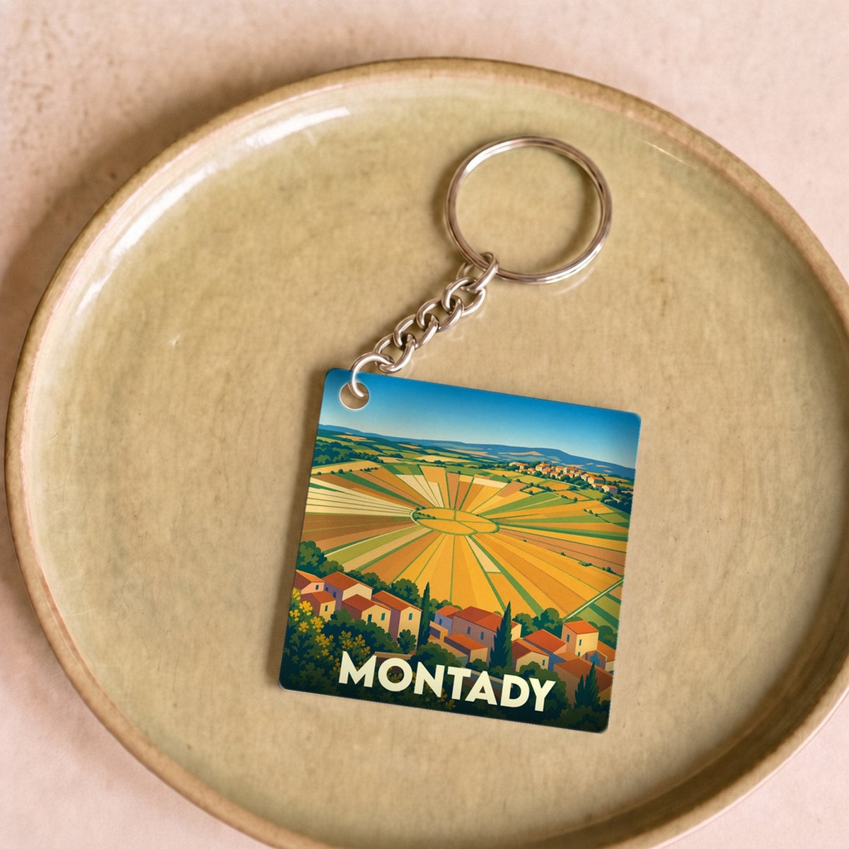 Porte-clés souvenir de la ville de Montady illustrant son célèbre étang asséché en forme de soleil.