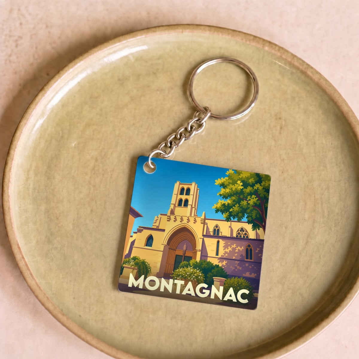 Porte-clés souvenir de la ville de Montagnac avec une illustration stylisée de son église.