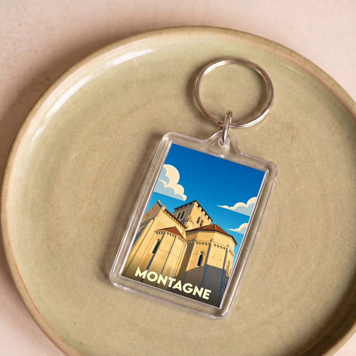 Porte-clés souvenir de la ville de Montagne avec une illustration stylisée de son église romane.