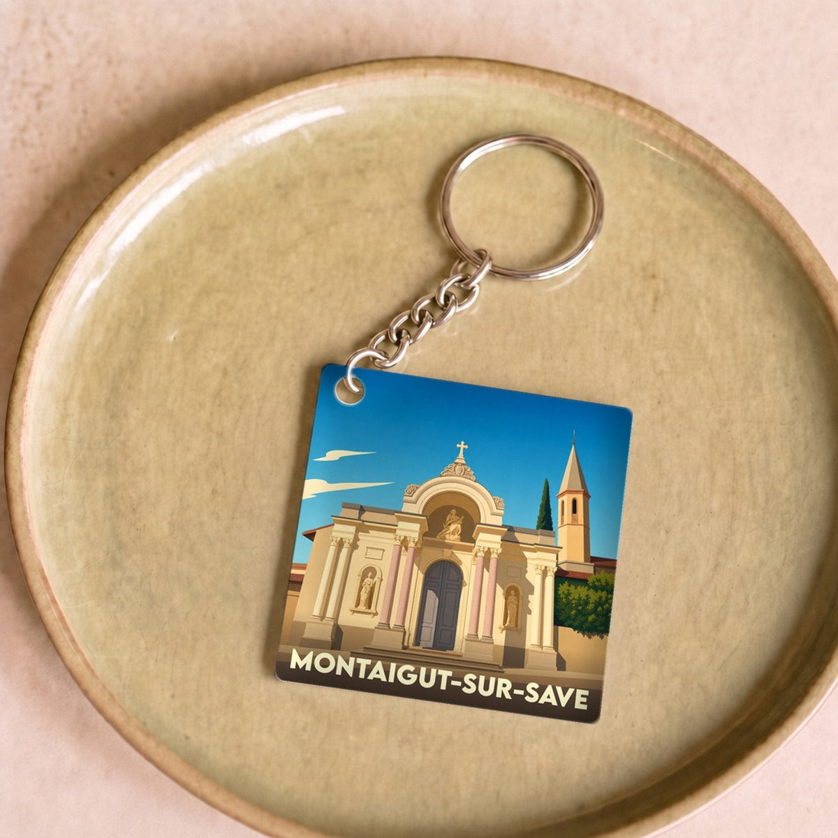 Porte-clés souvenir de la ville de Montaigut-sur-Save avec une illustration stylisée.